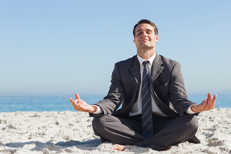 Business man meditating on beach